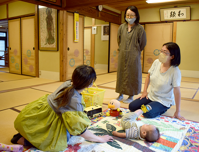 願生寺の客殿で実子をあやす藤井さんと語り合う中野さん、笹倉さん（右から）