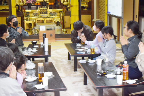 浄久寺本堂での食後に手を合わせる「おにぎりの日」の参加者