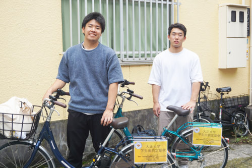 「学生出前定期便」専用の電動自転車で現場を訪問する広井さん（右）と梅宮さん