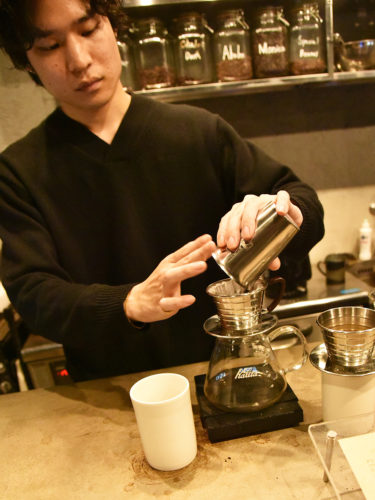 （画像①：丁寧な手仕事でコーヒーを入れる矢野CEO）