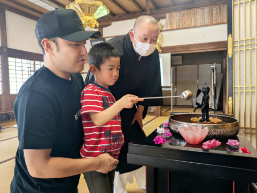 (画像花まつり:西光寺の花まつりで、誕生仏に甘茶をかける親子連れ)