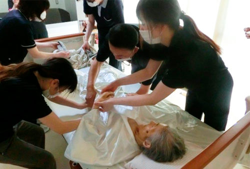 職員の手で白装束を着せる「納棺の儀」