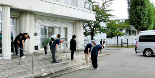 車が見えなくなるまでお見送りする職員ら