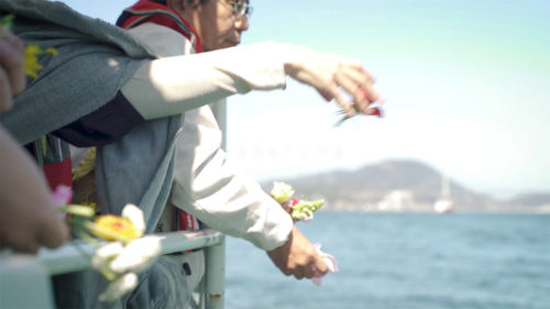 （画像２：海洋散骨の献花をする申込者（©mekarijinja））