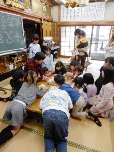 (画像2:本堂で将棋のルールを習う子どもたち)