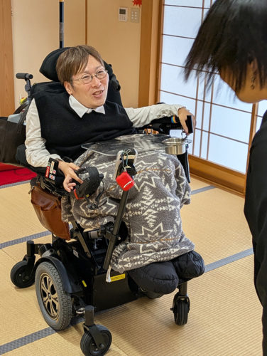 （画像１：語らいカフェのあと、参加者と談笑する川﨑さん＝鹿児島市）