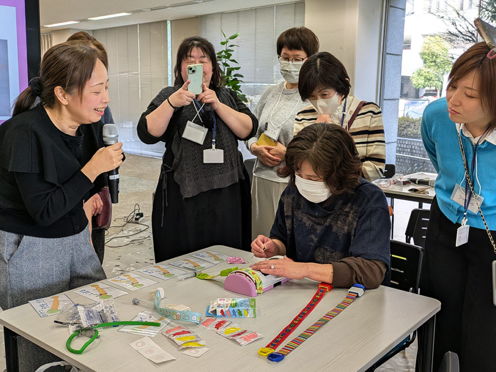 （画像アイキャッチ兼用：採血の練習キットを使って講演する河本さん（左）。子どもたちが心の準備をする大切さについて語った）