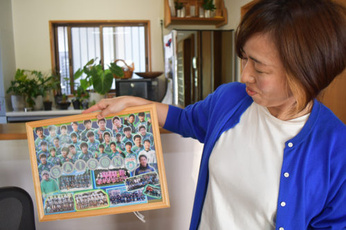 (画像2:夫の雄司さんが指導していたサッカークラブのメンバーの写真を眺める野田さん)